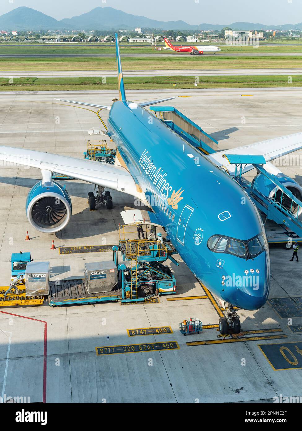 Vietnam Airlines Airbus A350 all'aeroporto internazionale noi Bai (NIA), il principale aeroporto di Hanoi, la capitale del Vietnam. Caricamento dei contenitori di carico Foto Stock