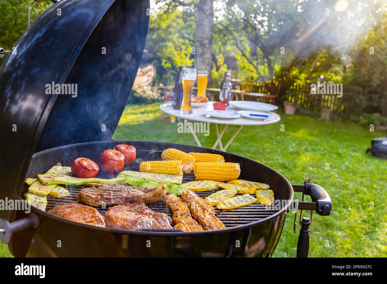 Barbecue in giardino, ci sono bistecche alla griglia, ma anche piatti vegetariani come pomodori, mais e zucchine, Muensingen, Baden-Wuerttemberg Foto Stock