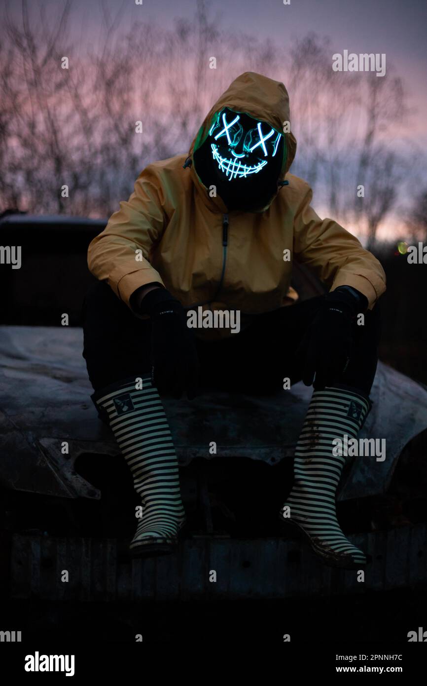 Maschera Purge, uomo con maschera LED su auto bruciata, stivali in gomma e  giacca da pioggia gialla, Francoforte sul meno, Assia, Germania Foto stock  - Alamy