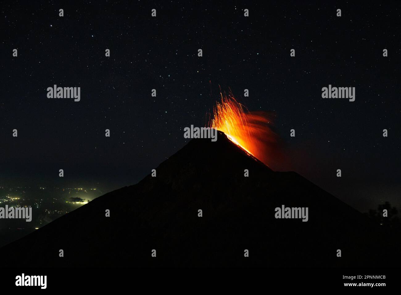 Un drammatico colpo di eruzione vulcanica, con una nuvola di cenere e lava che si innalza dalla cima di notte Foto Stock
