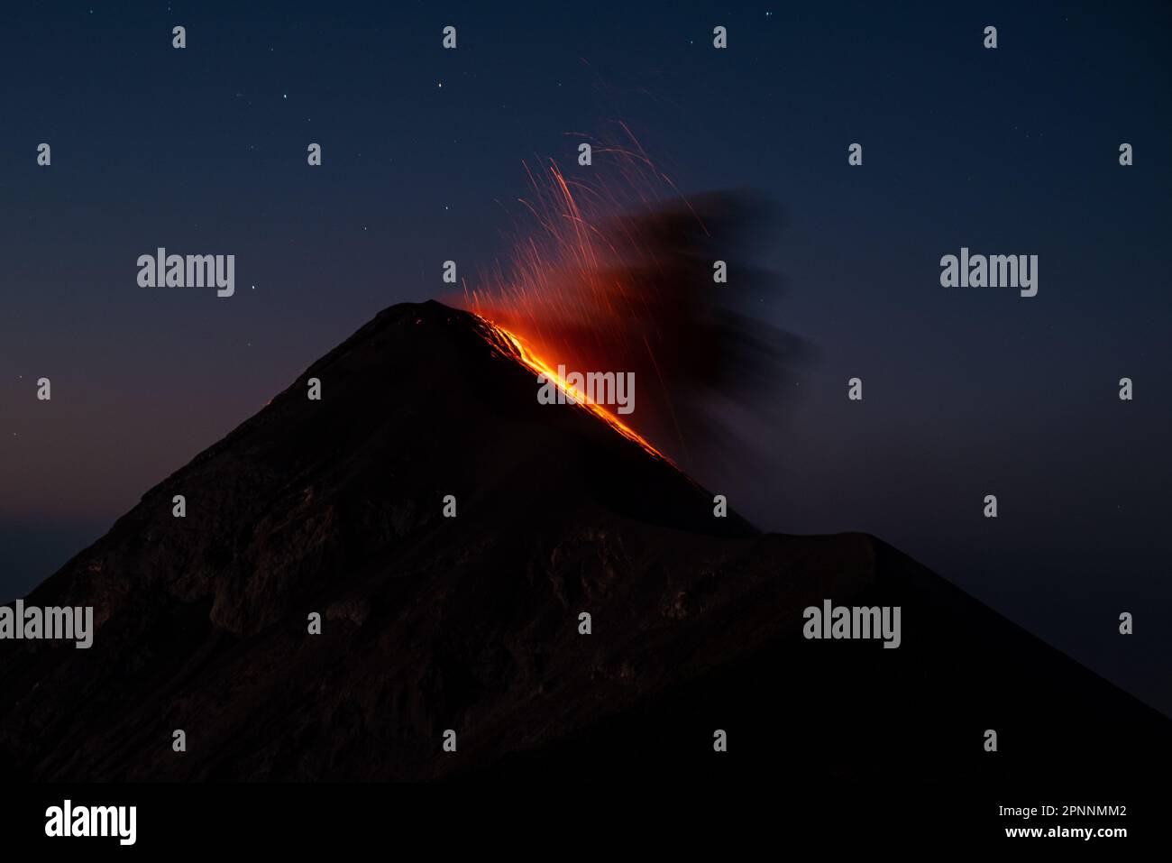 Una vista aerea di un vulcano attivo con un pennacchio di fumo e cenere che erutta dal suo cratere nel cielo Foto Stock