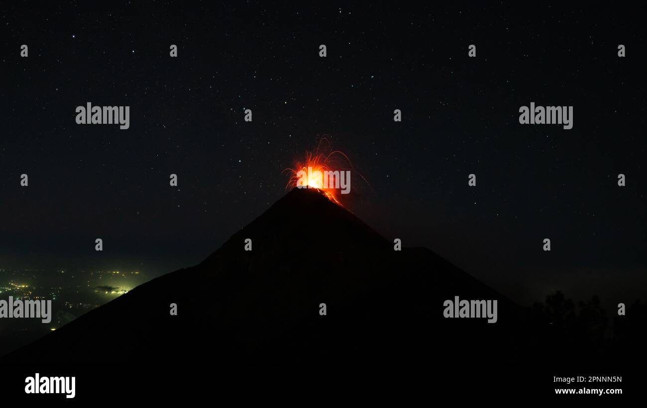 Un drammatico colpo di eruzione vulcanica, con una nuvola di cenere e lava che si innalza dalla cima di notte Foto Stock