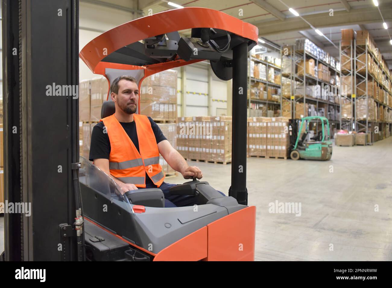 lavoratore di magazzino in un'agenzia di spedizione - interno con carrello elevatore a forche - trasporto e stoccaggio di merci Foto Stock