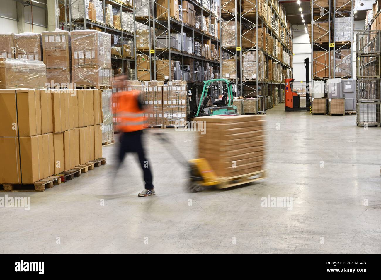 lavoratore di magazzino in un'agenzia di spedizione - interno con carrello elevatore a forche - trasporto e stoccaggio di merci Foto Stock