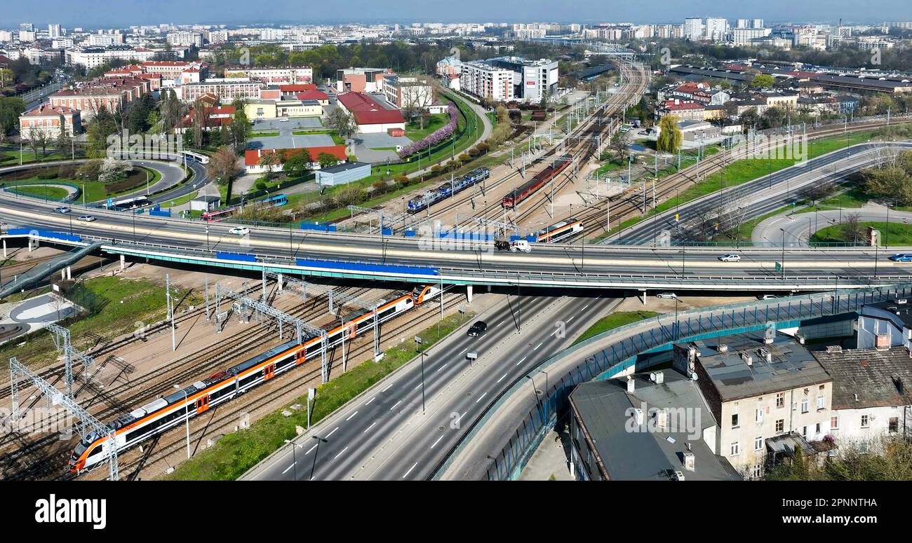 Cracovia, Polonia. Vari modi di trasporto vecchi e moderni: Ferrovie con treno e tram, autobus, auto e un taxi bianco con cavalli neri sul multi-lev Foto Stock