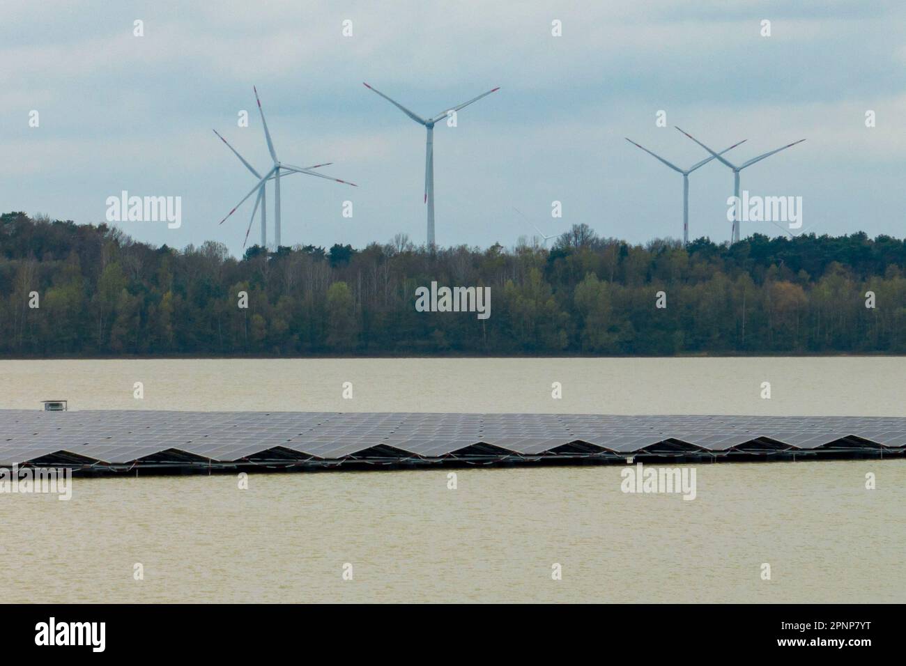 Haltern am See, Germania. 20th Apr, 2023. La centrale solare galleggia sul Lago d'Argento III. Alcune turbine eoliche possono essere viste in background. La più grande centrale solare galleggiante della Germania è in funzione a Haltern da quasi un anno e ha una produzione di ben 3,1 megawatt, secondo l'Associazione di Stato per le energie rinnovabili. Credit: Christoph Reichwein/dpa/Alamy Live News Foto Stock