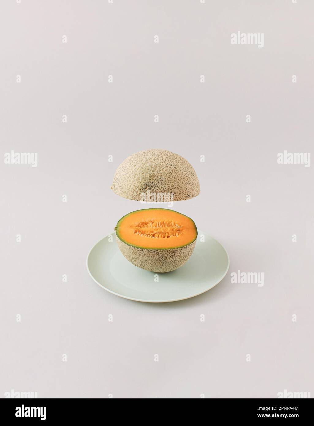 Melone fresco con mezza levitazione tagliata. Concetto di frutta estiva minima. Foto Stock