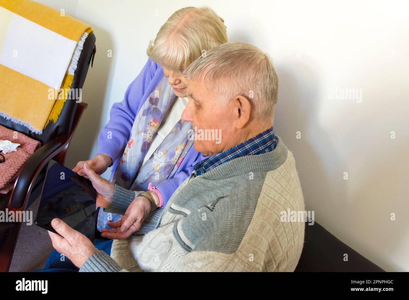 Coppia anziana che utilizza un computer tablet con connessione wifi a banda larga. Foto Stock