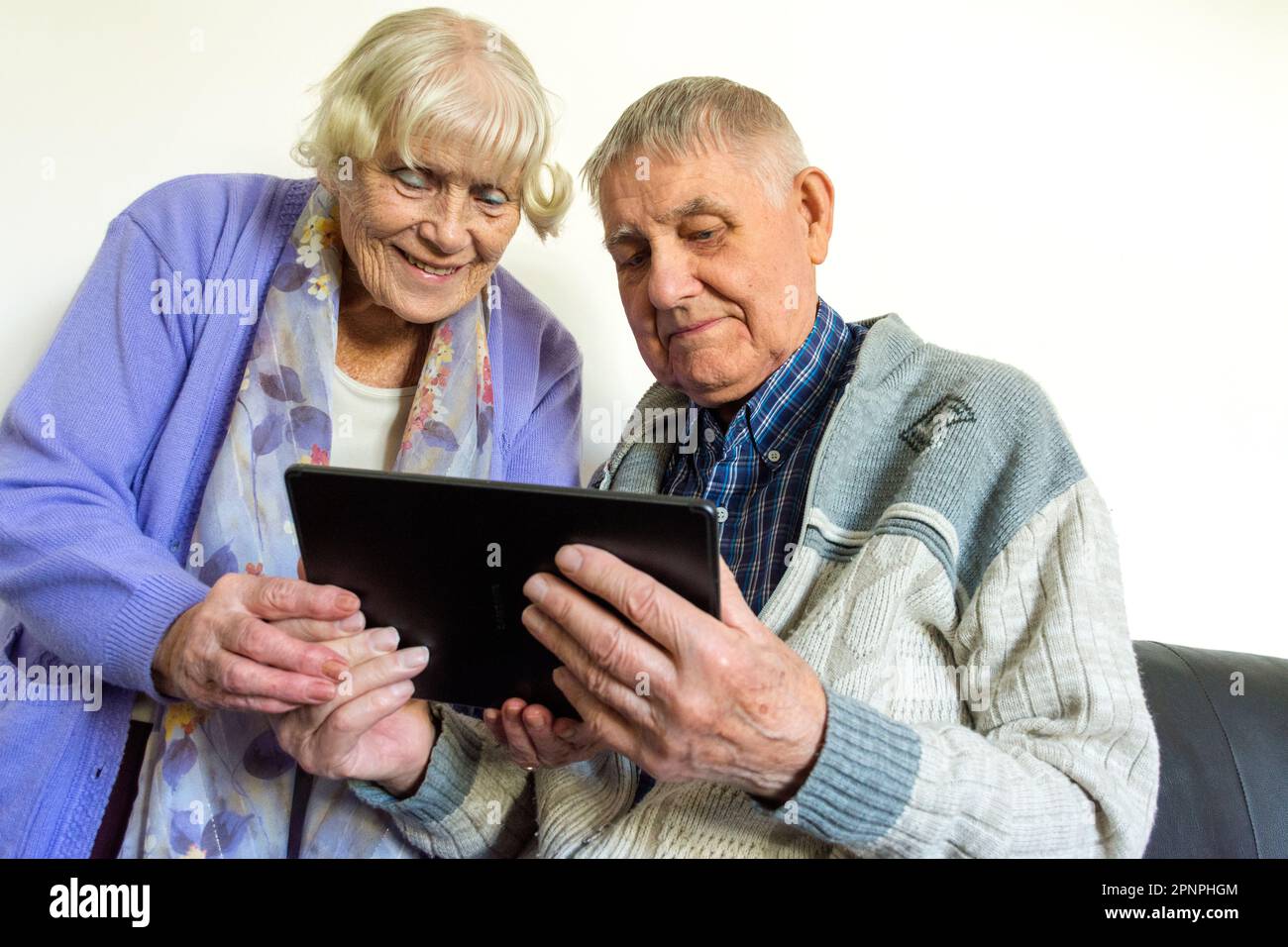 Coppia anziana che utilizza un computer tablet con connessione wifi a banda larga. Foto Stock