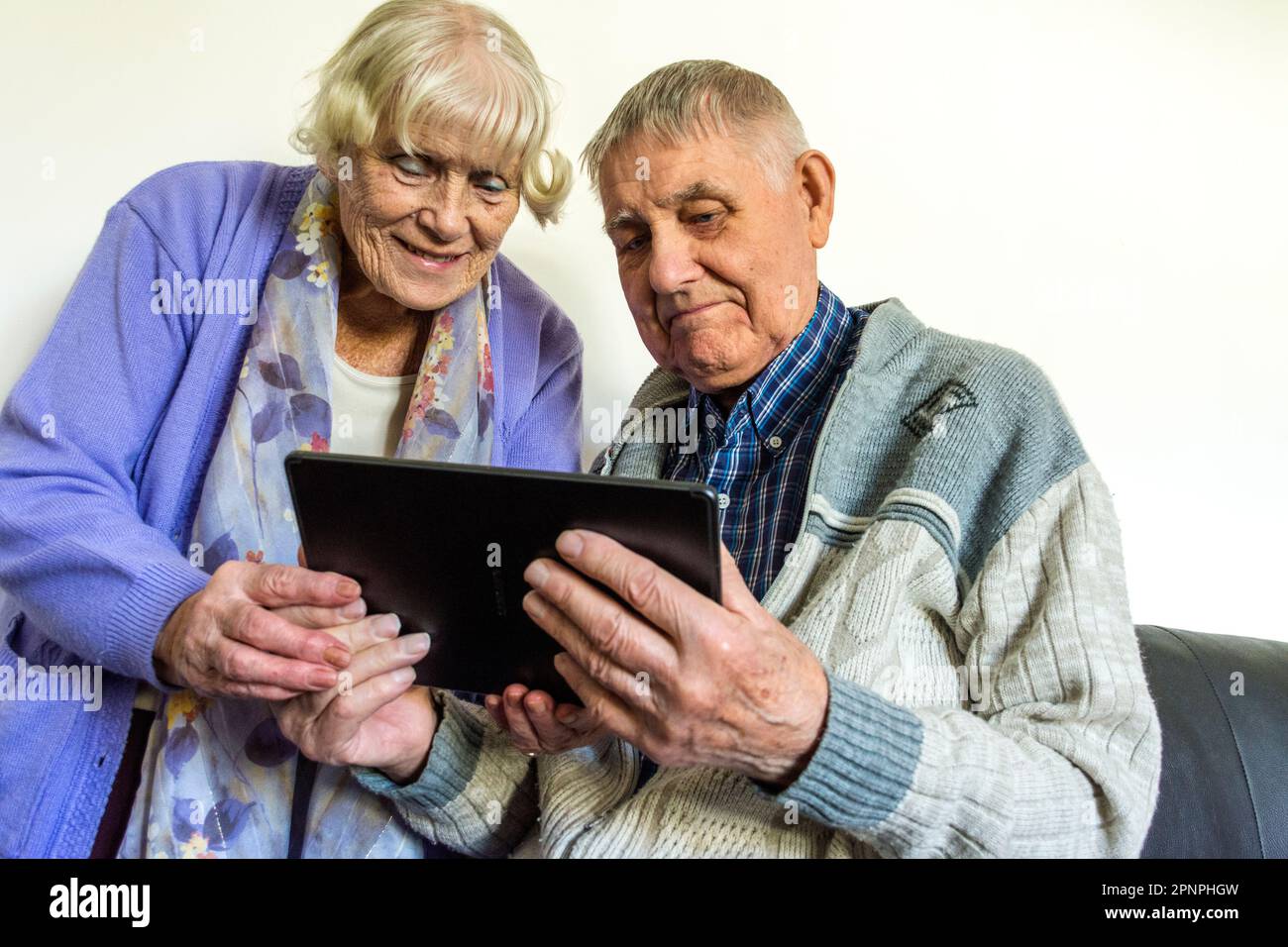 Coppia anziana che utilizza un computer tablet con connessione wifi a banda larga. Foto Stock