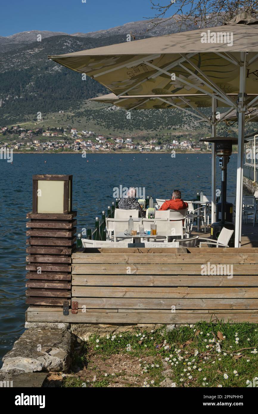 I turisti si rilassano in una caffetteria che si affaccia sul Lago Ioannina in Grecia in primavera Foto Stock