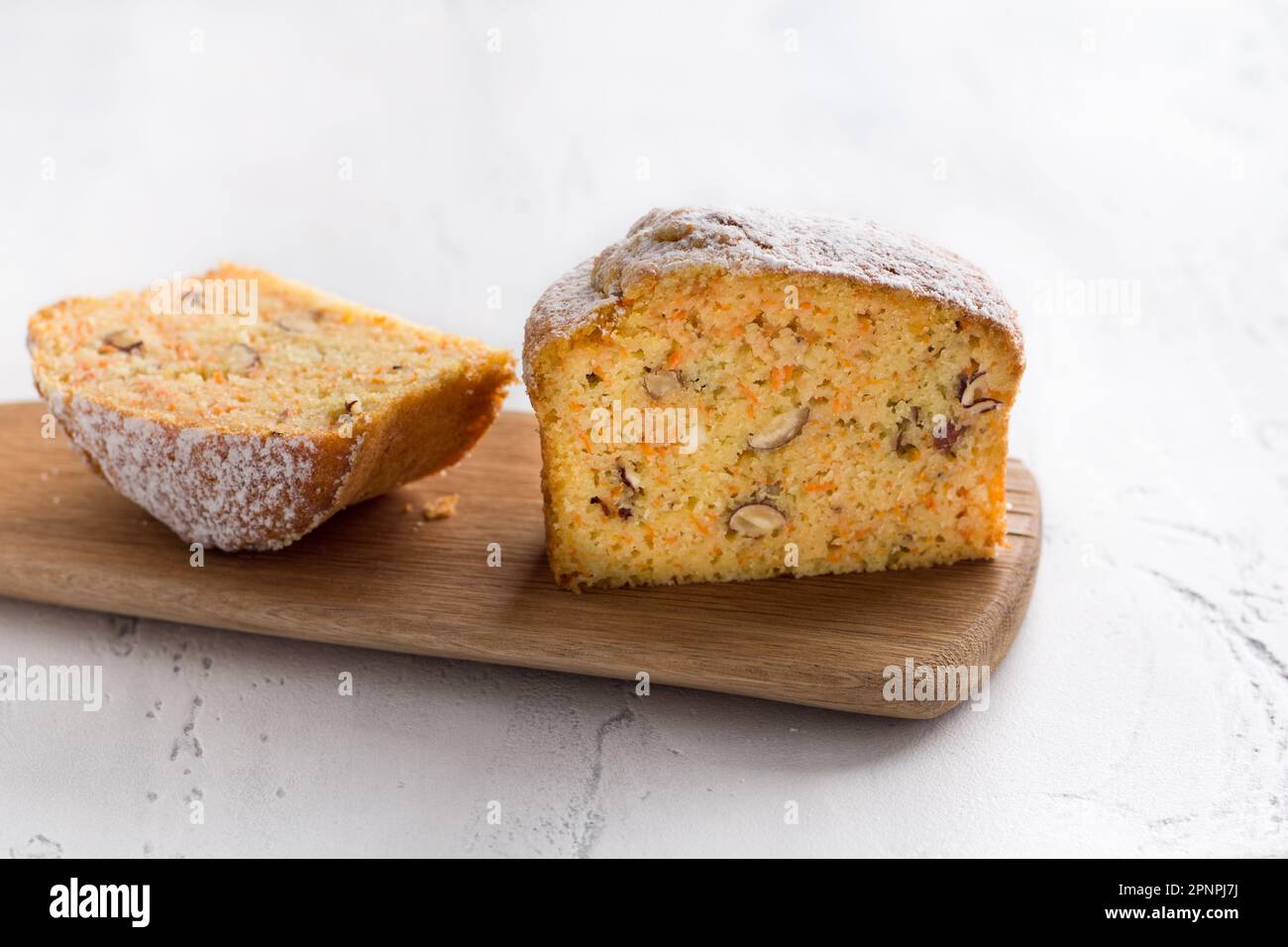 Torta di semola di carote o mannik dolce appena sfornato con noci cosparse di zucchero a velo su sfondo azzurro Foto Stock
