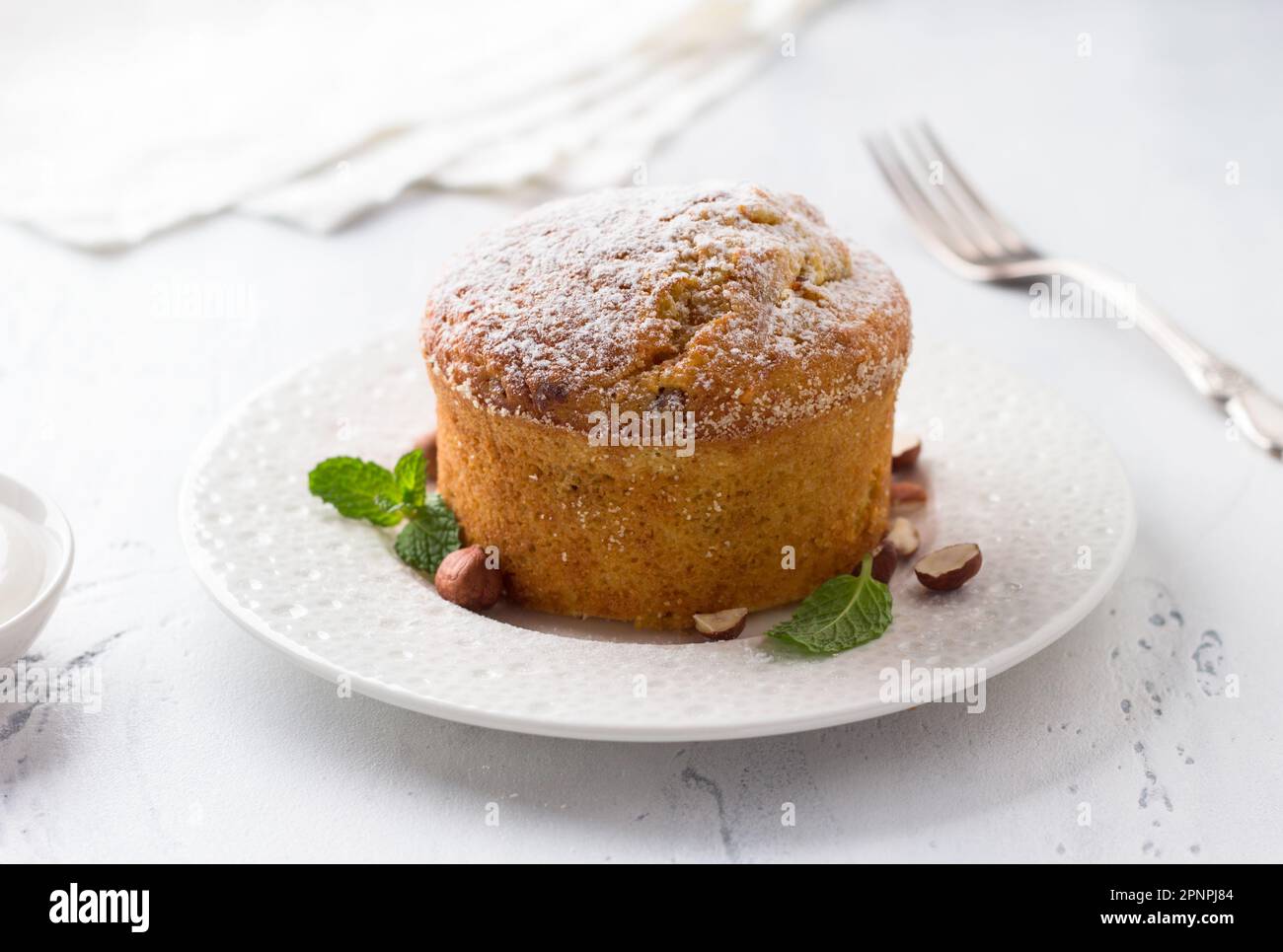 Torta di semola di carote o mannik dolce appena sfornato con noci cosparse di zucchero a velo su sfondo azzurro Foto Stock