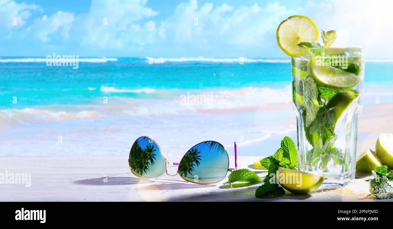 Tropico vacanza estiva; drink esotici sulla sfocatura spiaggia tropicale sfondo Foto Stock