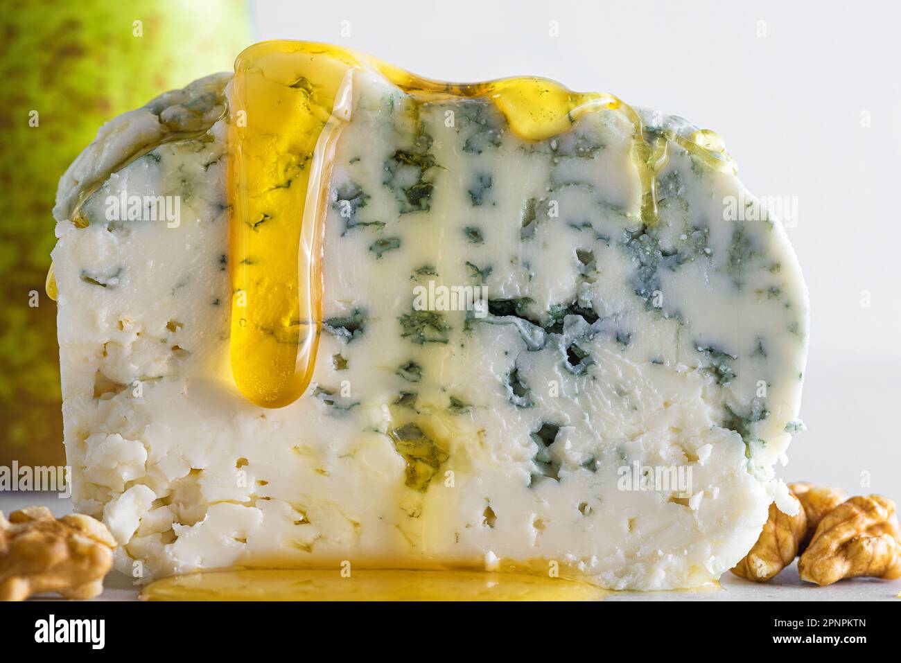 Formaggio blu con miele, pera e noci su fondo bianco. Antipasto italiano. Cibo gustoso Foto Stock