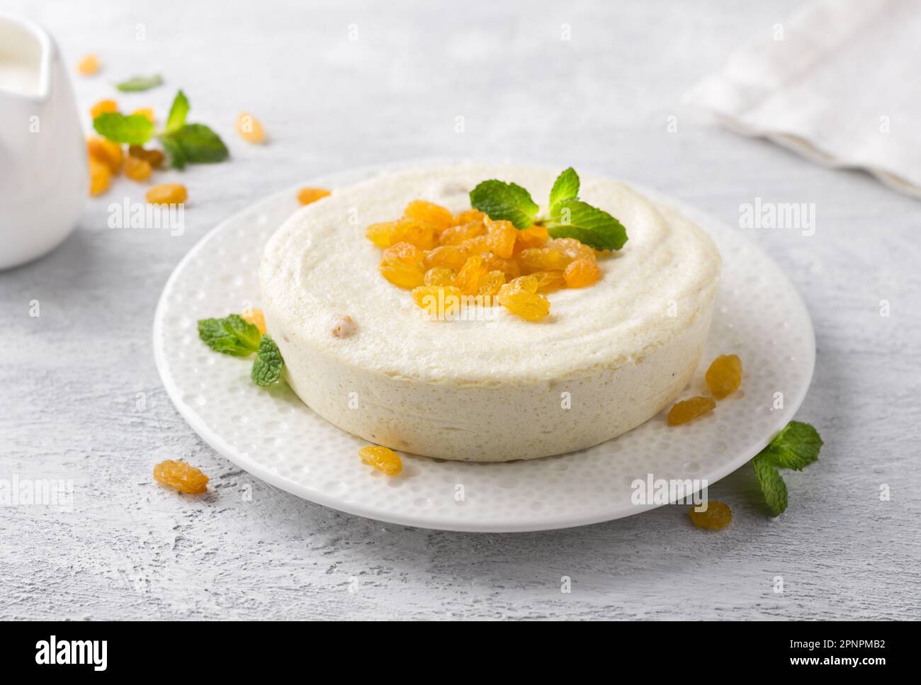 Delicata casseruola di formaggio a vapore Cottage con uvetta decorata con menta su sfondo grigio chiaro. Deliziosi piatti vegetariani fatti in casa Foto Stock