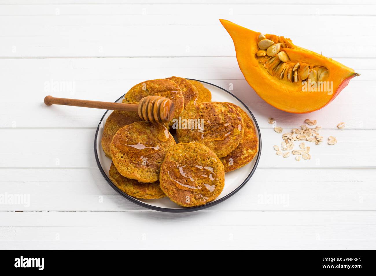 Frittelle di zucca sane con farinata d'avena sgocciolata con miele su sfondo bianco. Delizioso cibo vegetariano Foto Stock