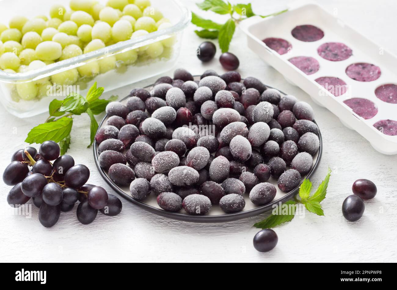 Metodi di congelamento delle uve: Surgelate, congelate con zucchero e puree congelate su fondo grigio chiaro. Preparazioni sane fatte in casa Foto Stock