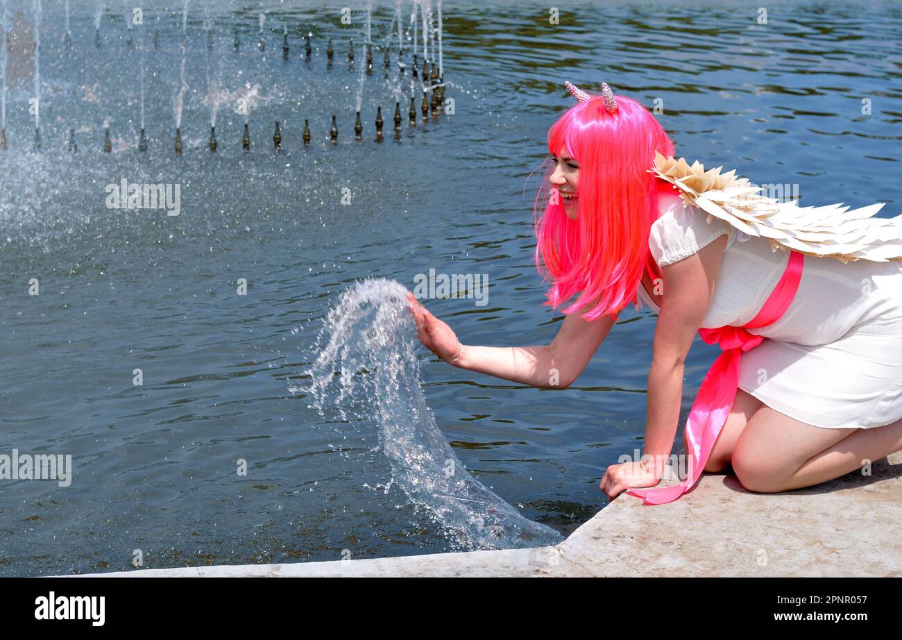 donna attraente in costume demone raffreddamento vicino alla fontana in tempo caldo Foto Stock