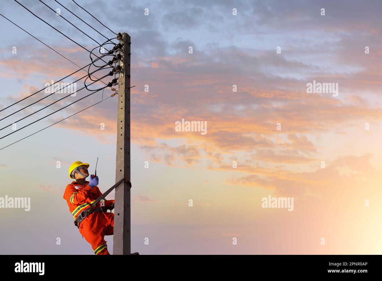 Elettricista scalando un pilone elettrico per riparare una linea elettrica, Thailandia Foto Stock