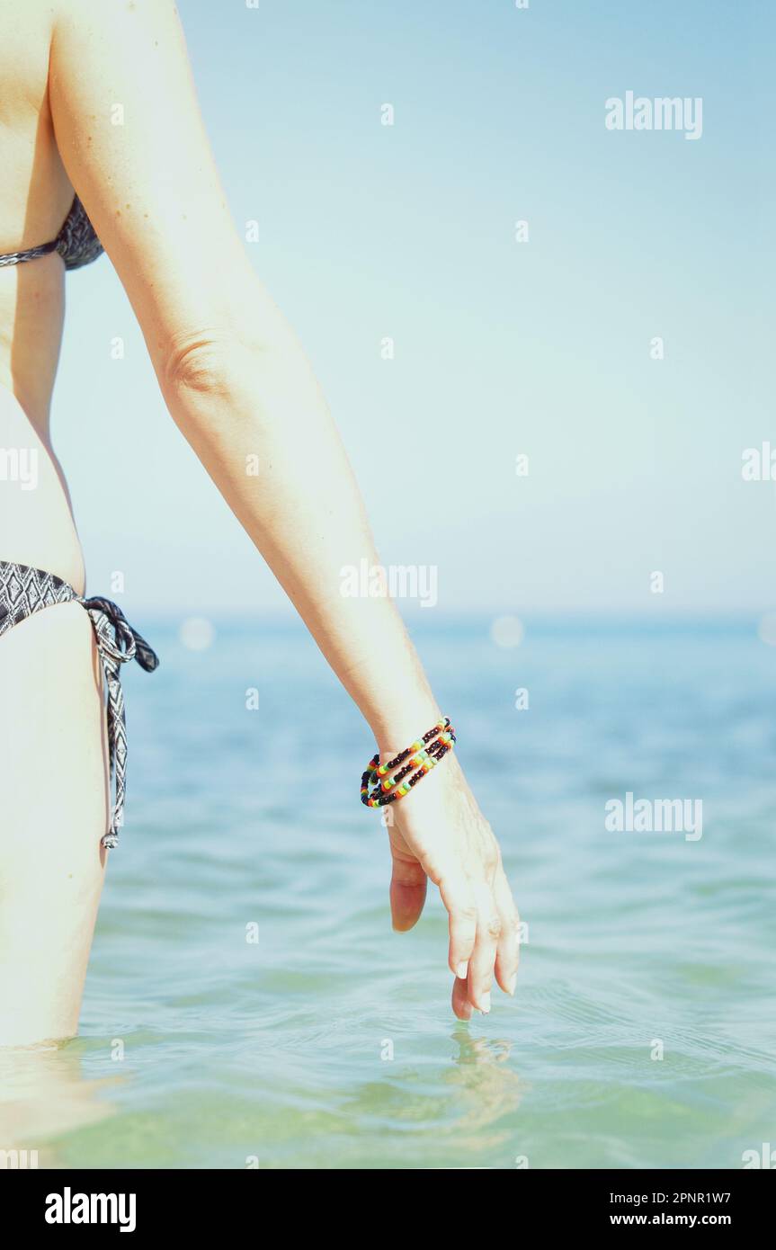 Vista posteriore primo piano di una donna in un bikini in piedi nel mare, Giamaica Foto Stock
