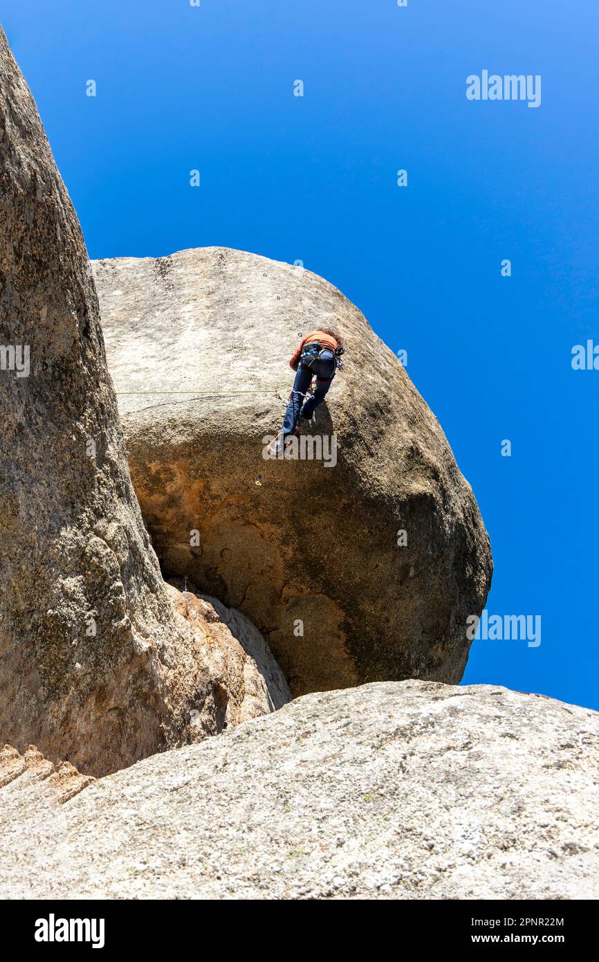 Giovane adulto che si arrampica su uno sbalzo di granito a Torrelodones, Madrid. Arrampicata su roccia. Concetto di sport estremi Foto Stock