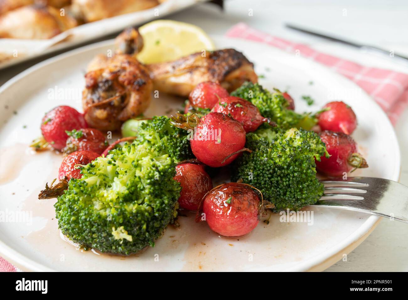 Contorno di verdure sane per cena o pranzo con ravanello rosso arrosto in padella e broccoli marinati con miele, olio d'oliva e succo di limone Foto Stock