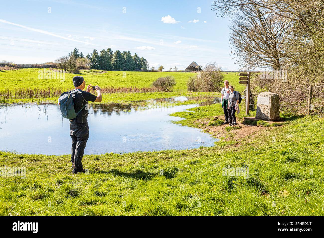 Persone all'inizio del Thames Path alla fonte del Tamigi a Tamigi testa sul Cotswolds vicino a Kemble, Gloucestershire UK. Foto Stock