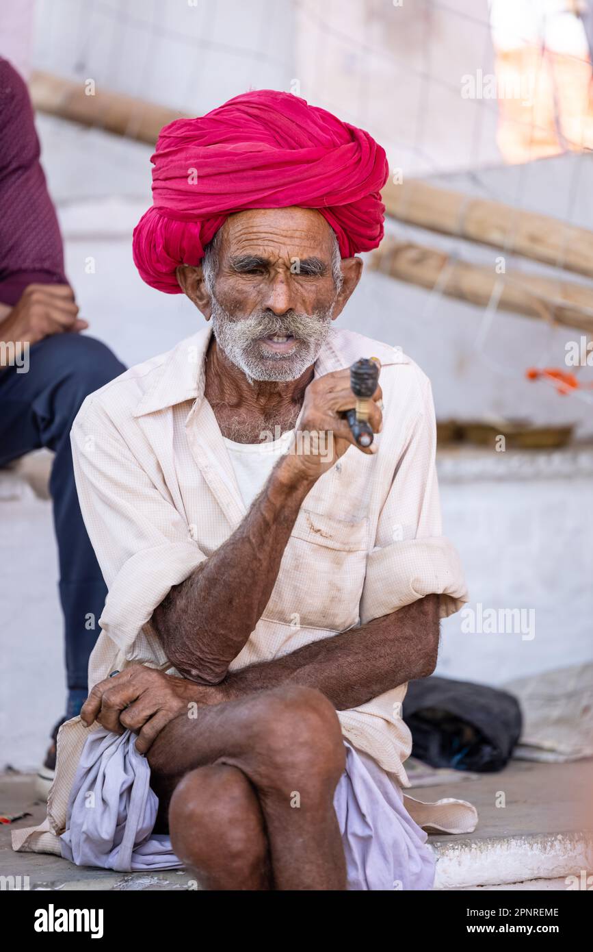 Pushkar, India - ottobre 2022: Fiera di Pushkar, Ritratto di un vecchio maschio rajasthani con abiti tradizionali bianchi e turbano colorato al terreno fieristico di pushkar Foto Stock