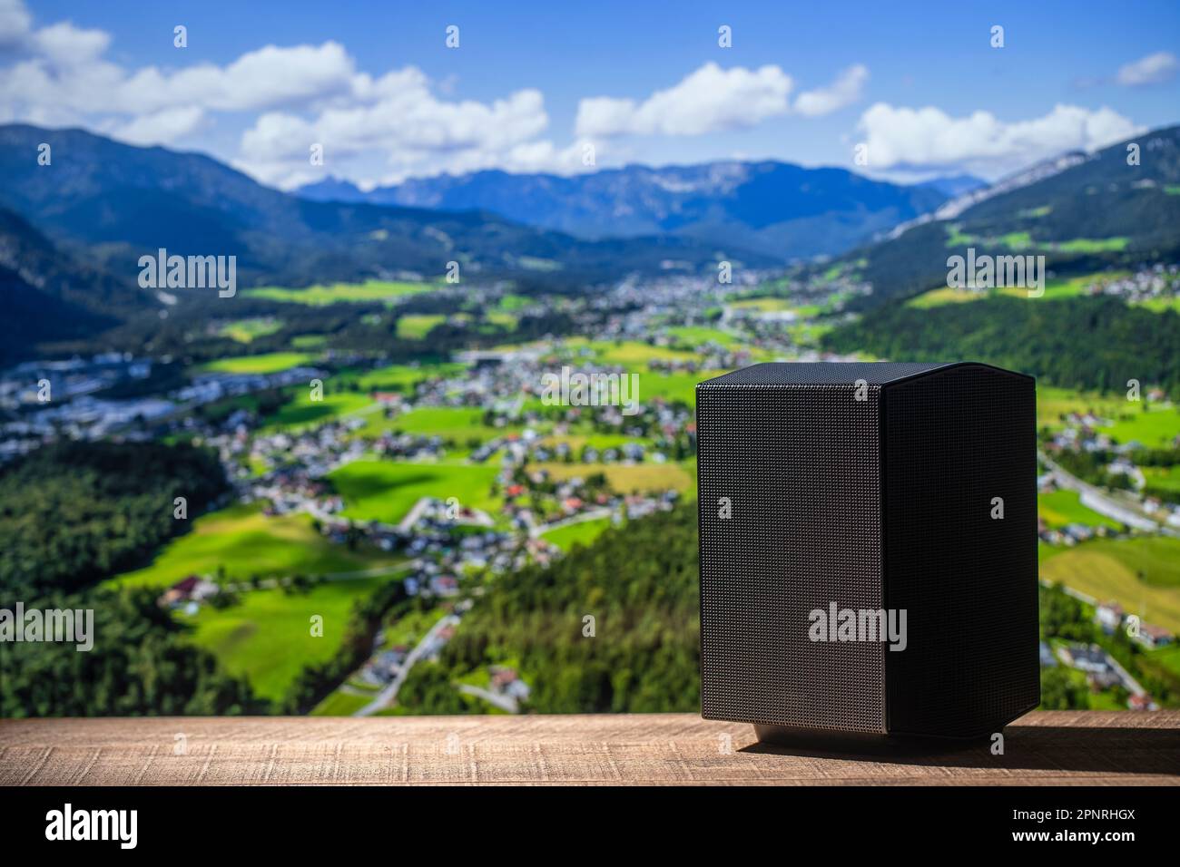 Altoparlante acustico nero su un tavolo di legno sullo sfondo delle montagne alpine in Austria. L'attrezzatura musicale, primo piano Foto Stock