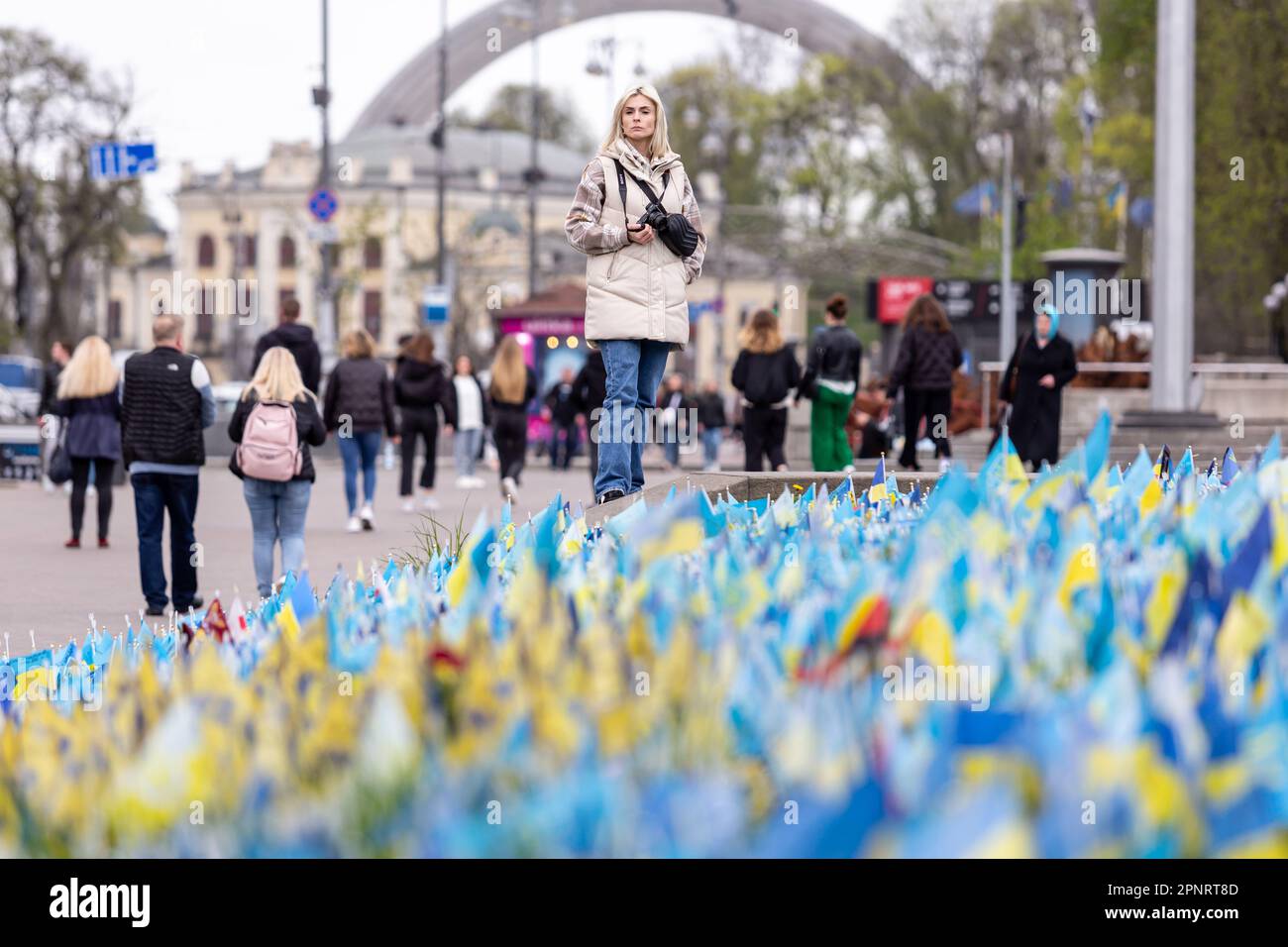 Una donna si ferma dalle bandiere nazionali ucraine blu e gialle con i nomi dei soldati caduti su Maidan Nezalezhnosti (Piazza dell'Indipendenza) nel centro di Kyiv, la capitale dell'Ucraina. Le famiglie e gli amici dei militari uccisi lasciano le bandiere come un memoriale per i loro cari mentre l'invasione completa dell'Ucraina da parte delle forze russe continua. Foto Stock