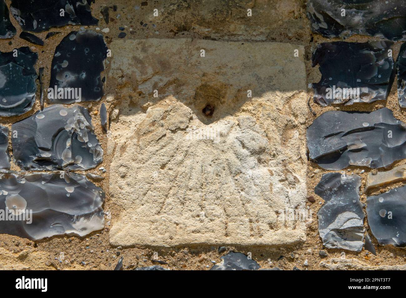 I resti di una meridiana graffiata su un contrafforto incorniciato da flint flushwork presso la chiesa di Santa Maria Vergine di Parham, Suffolk Foto Stock