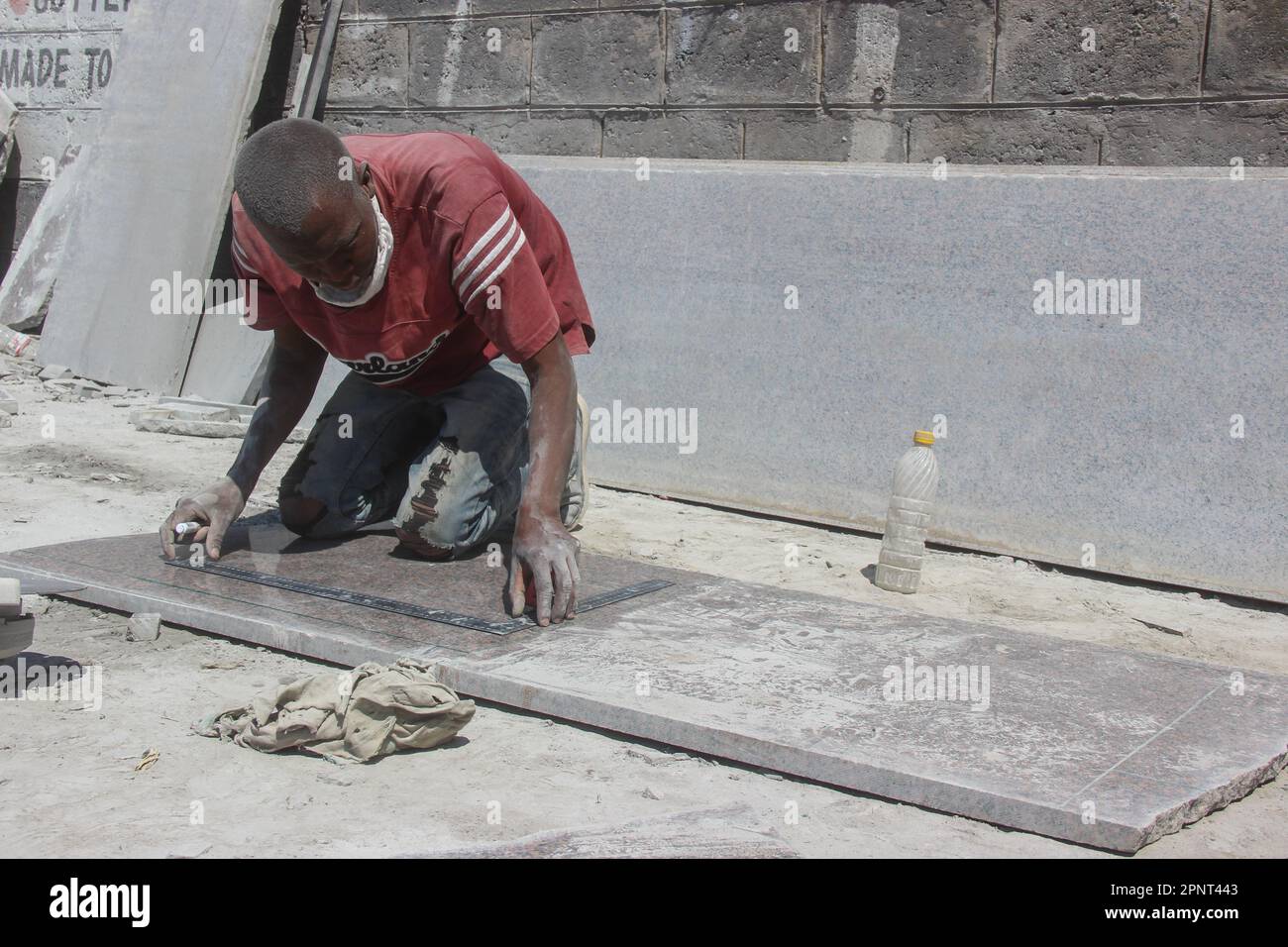 Francis Lubinda misura una pietra granitica mentre progetta una lapide nel quartiere centrale degli affari di Lusaka, Zambia, il 20 agosto 2021. I funerali sono stati limitati per limitare la diffusione del coronavirus, e molte famiglie stanno trovando la chiusura ponendo lapidi sulle tombe dei cari. (Pruvidence Phiri/Global Press Journal) Foto Stock