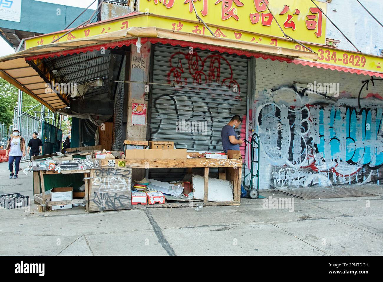 New York, NY USA - 06 27 2022: Empty Chinatown Stall con consegna persona con camion a mano Foto Stock