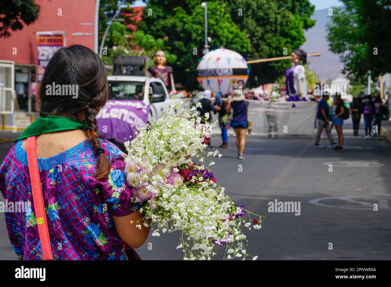 Una donna tiene fiori in una marcia in occasione della Giornata internazionale della donna a Oaxaca de Juárez, Oaxaca, Messico, il 8 marzo 2022. I partecipanti hanno protestato contro la violenza di genere in Messico, dove ogni giorno vengono uccise in media 10 donne. (ENA Aguilar Peláez/Global Press Journal) Foto Stock