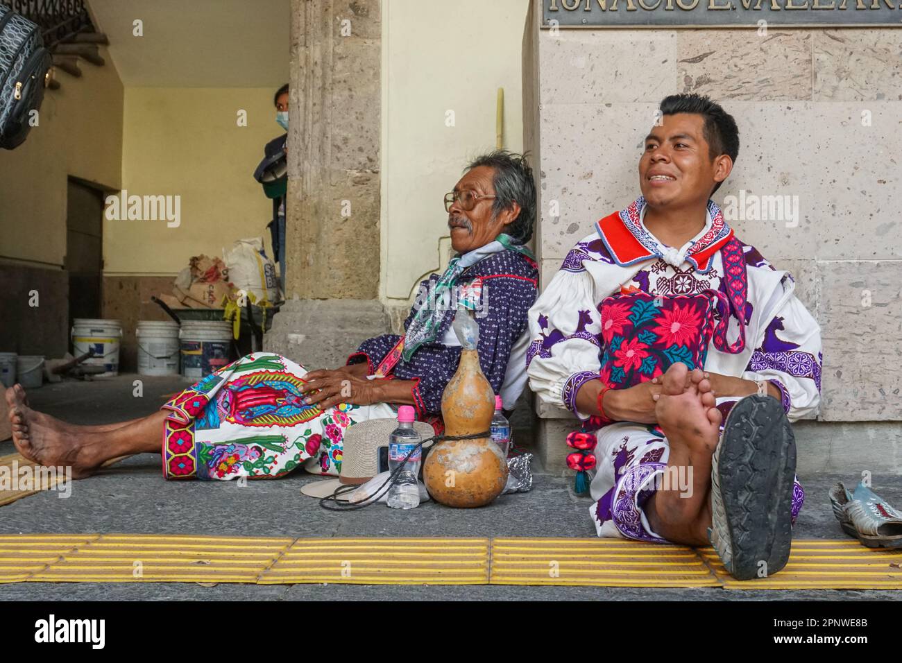 Aurelio Carrillo Carrillo, a sinistra, e suo figlio Agustín Carrillo de la Cruz riposano nel centro della città di Guadalajara, Jalisco, Messico il 6 maggio 2022, dopo aver camminato per oltre 270 chilometri (168 miglia) dal nord di Jalisco. Fanno parte di un gruppo di oltre 200 Wixaritari che viaggiano a Città del Messico per richiedere la restituzione di oltre 10.500 ettari (25.946 acri) di terreno. (Maya Piedra/Global Press Journal) Foto Stock