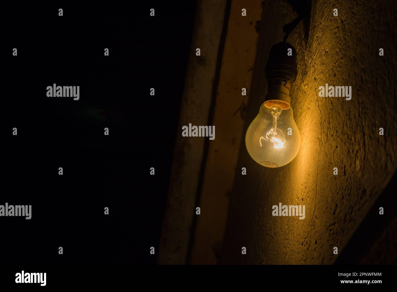 La lampadina al tungsteno giallo incandescente è illuminata contro una parete con filamento incandescente con elettricità. Questi sono stati principalmente utilizzati in famiglia. Foto Stock