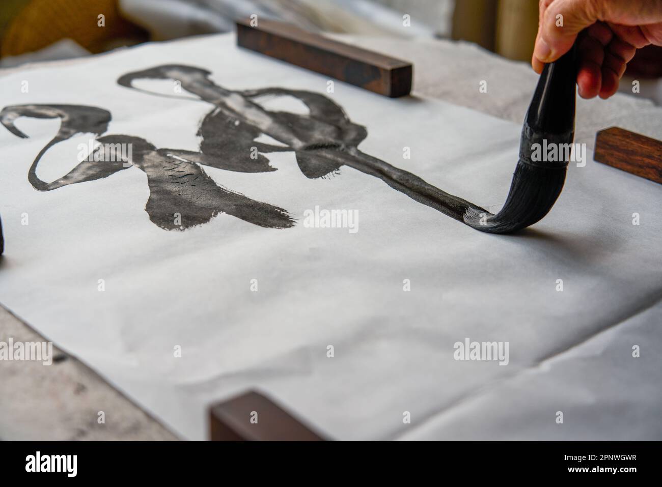 Un vecchio calligrafo cinese sta scrivendo caratteri pennello, creando opere di calligrafia cinese. Traduzione: Viene la primavera, arriva il dio del vento. Foto Stock