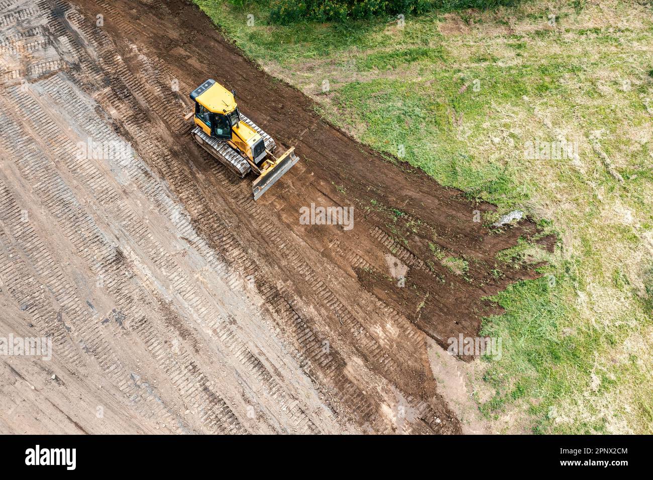 il bulldozer cingolato giallo esegue lavori di terra in cantiere. vista aerea dal drone volante. Foto Stock