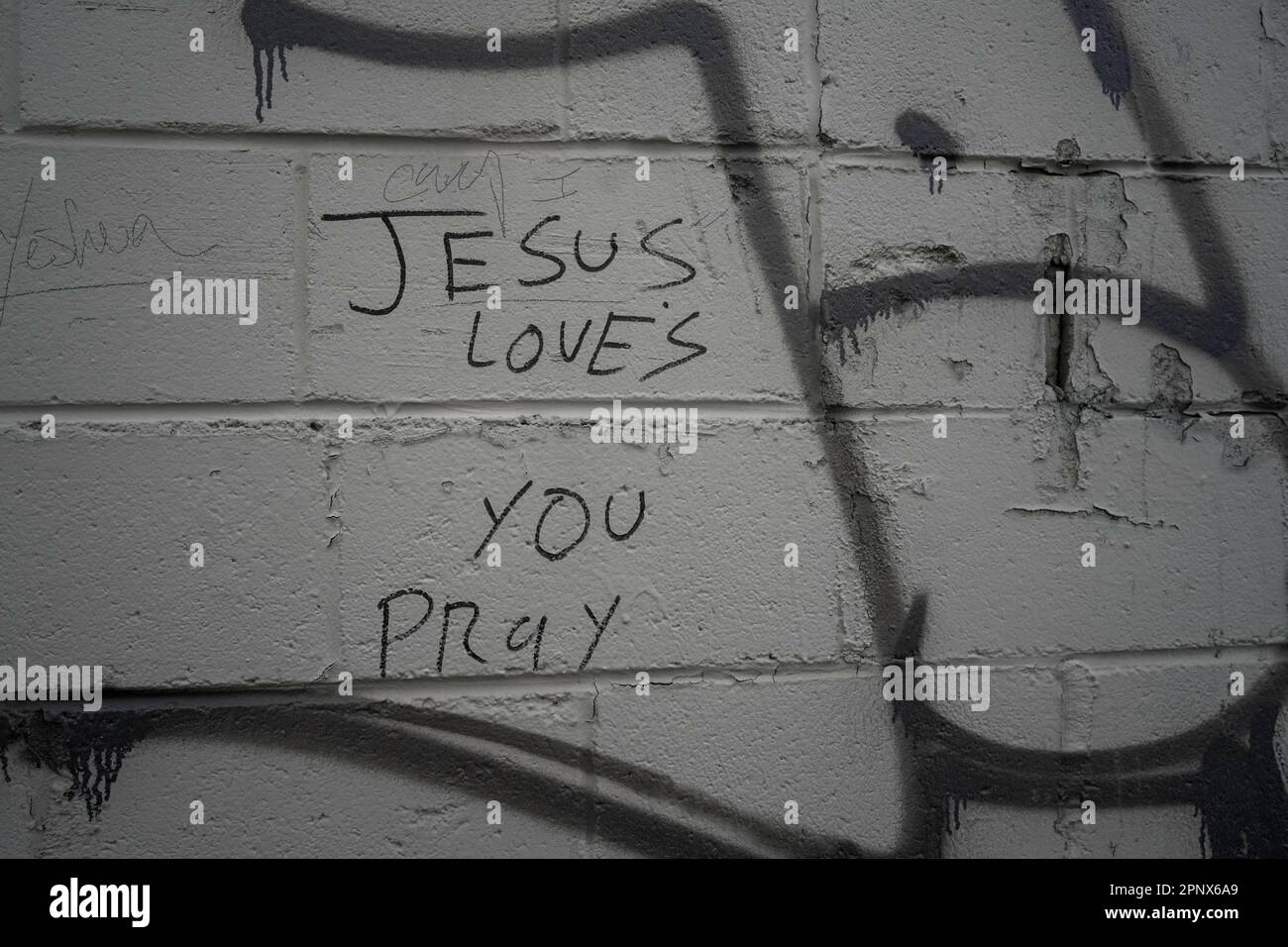Gesù ti ama pregare sharpie scrivere su un muro di mattoni dipinti Foto Stock