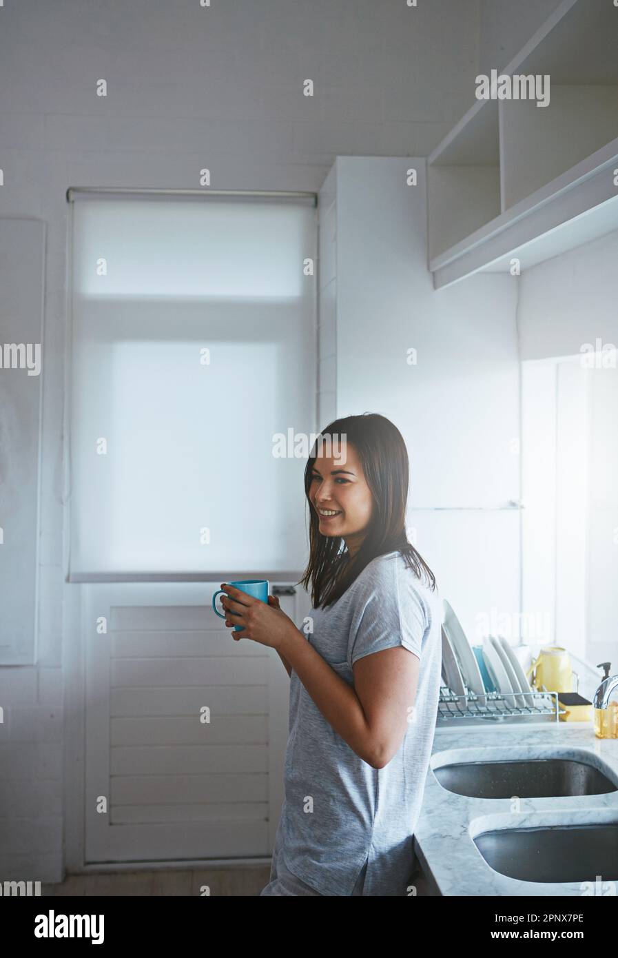 Godendo di un inizio lento alla sua giornata. una giovane donna attraente che si gode un caffè in piedi in cucina. Foto Stock
