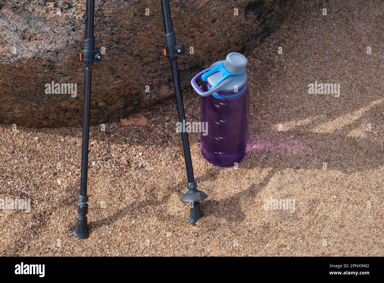 Bastoncini da trekking e bottiglia d'acqua nella spiaggia di sabbia Foto Stock