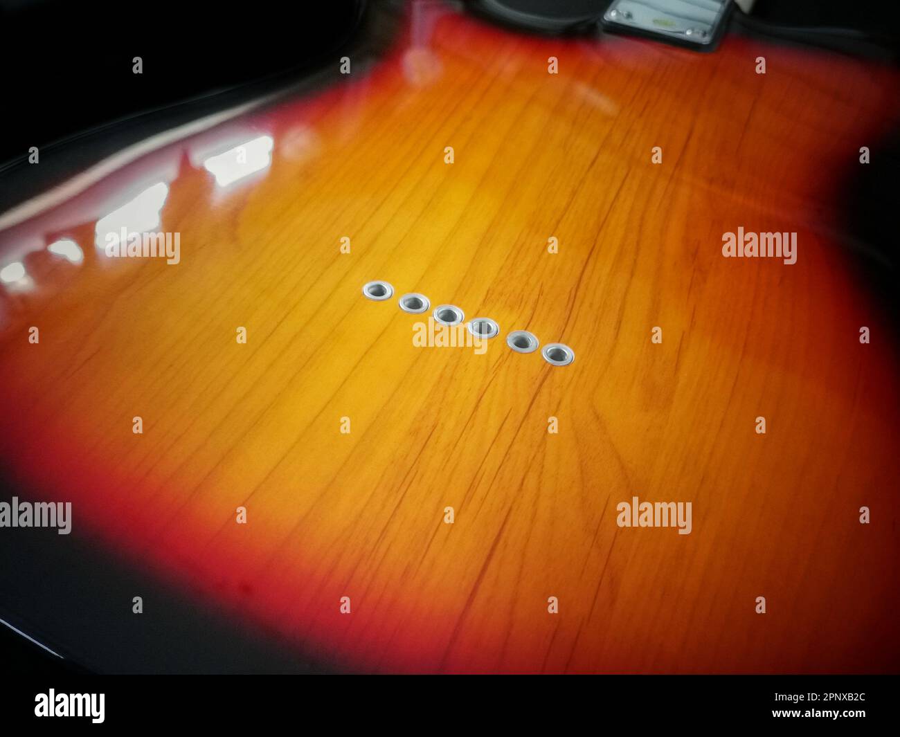 Primo piano di buchi per String nella parte posteriore elettronica dello stile del corpo della chitarra Foto Stock