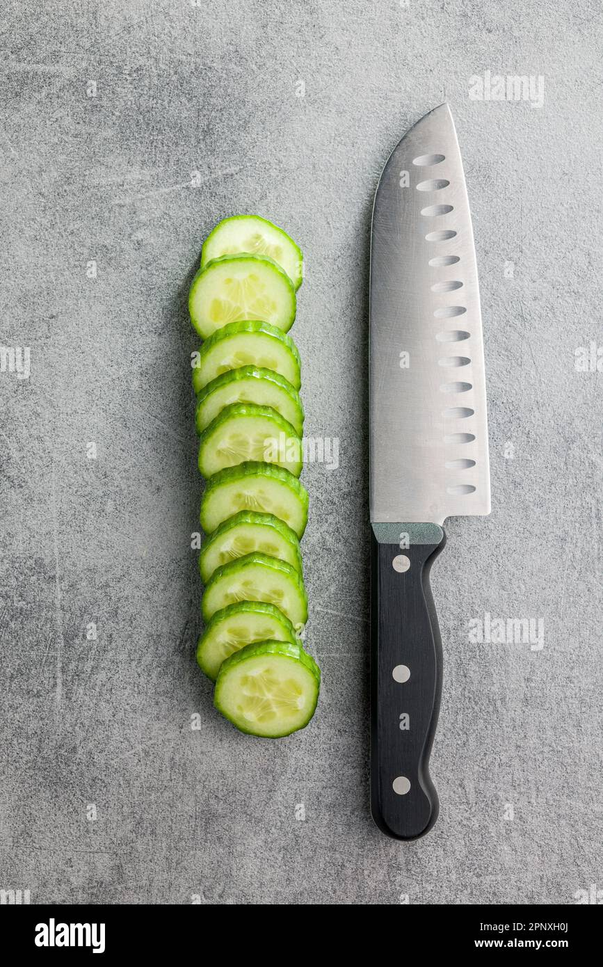 Cetriolo verde fresco a fette e coltello sul tavolo da cucina. Vista dall'alto. Foto Stock