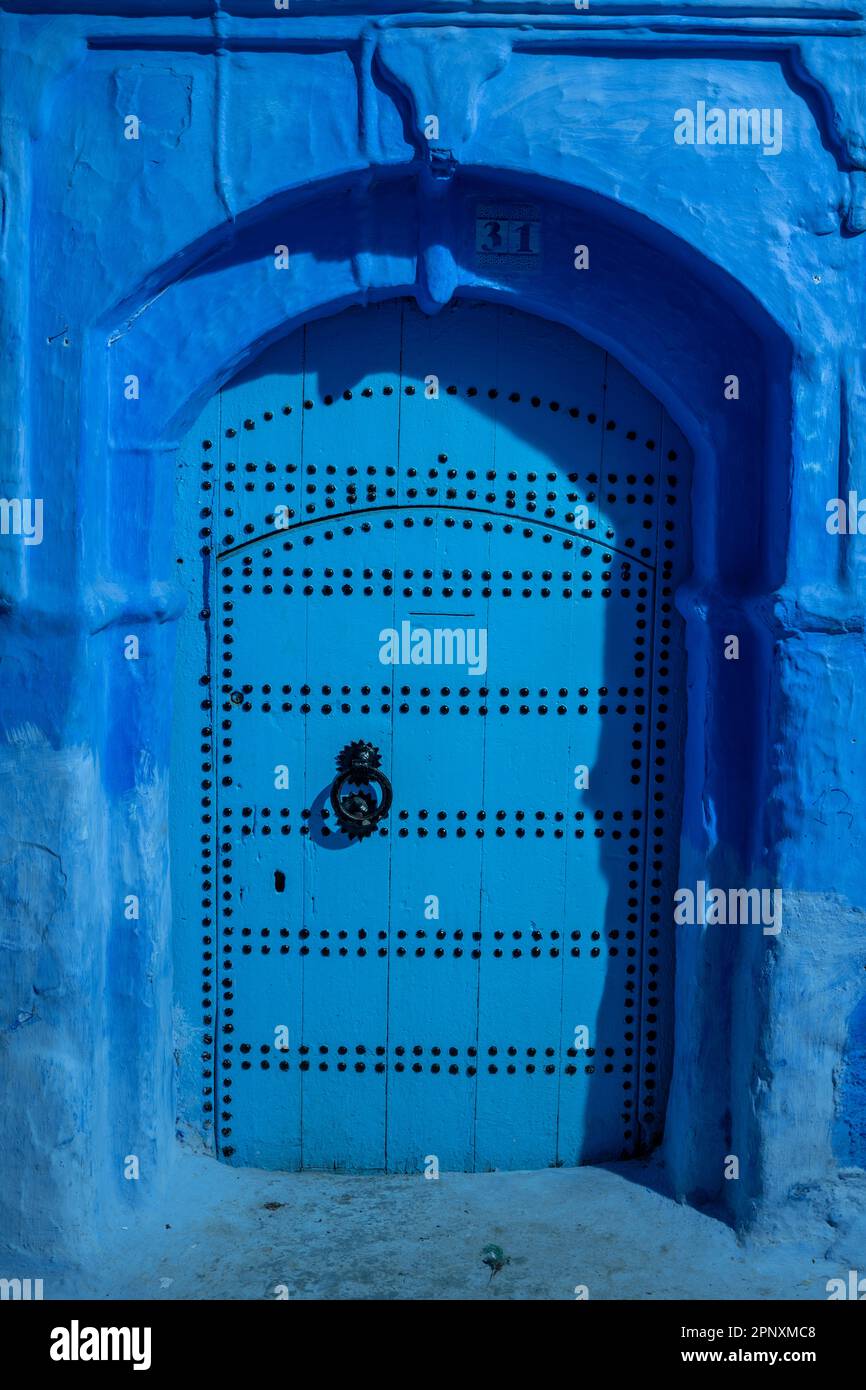 Porta di una casa nelle strade blu di Chefchaouen, illuminata da luce artificiale di notte. Foto Stock