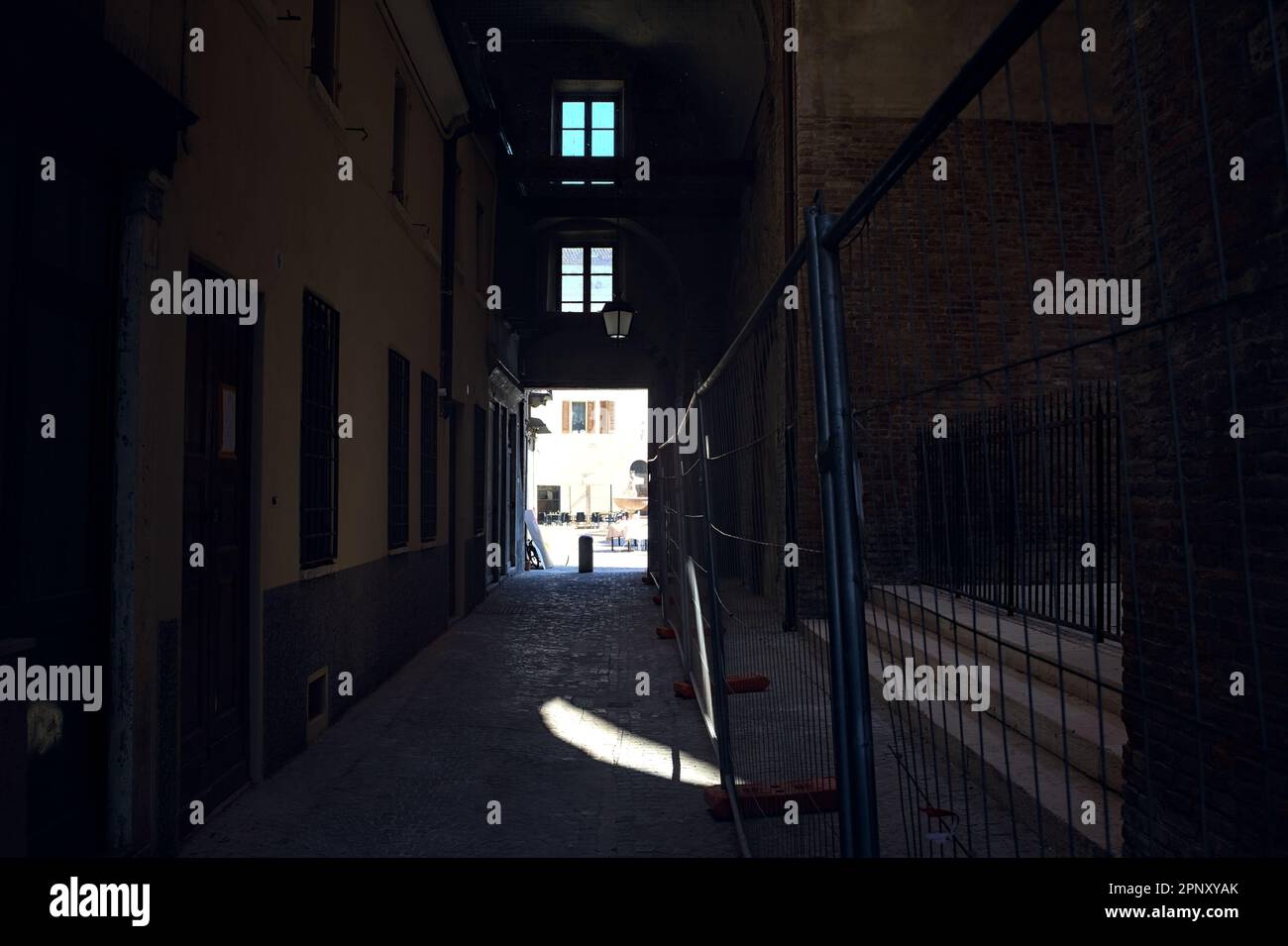 Vicolo coperto sotto un palazzo che termina in una piazza in una città italiana in una giornata di sole Foto Stock