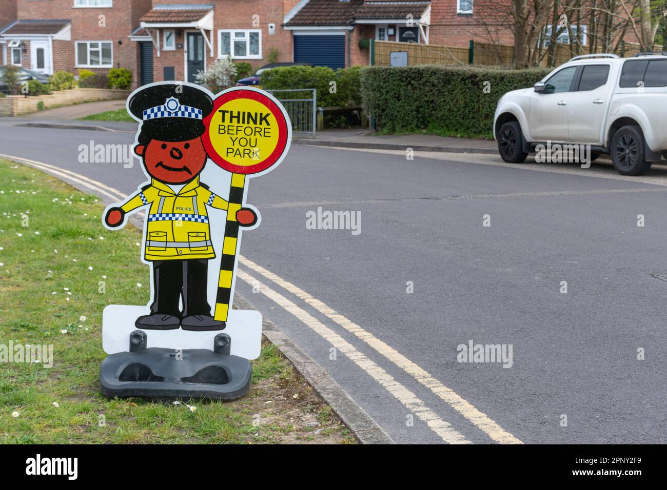 Divertente segno fuori di una scuola con un poliziotto e lollipop segno lettura pensare prima di parcheggiare, Inghilterra, Regno Unito. Sicurezza stradale presso il punto di rientro a scuola Foto Stock