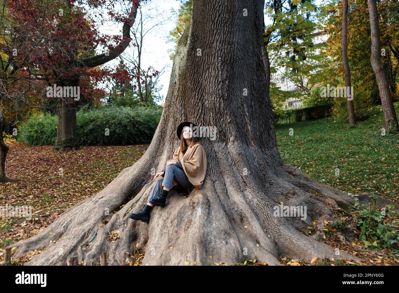 donna dai capelli castani in un cappello nero e poncho nel parco Foto Stock