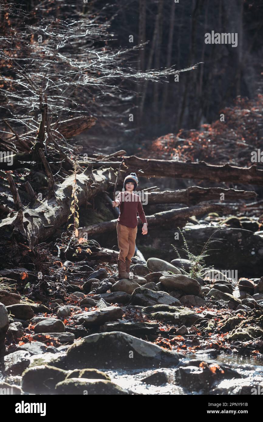 Bambini che giocano con il bastone accanto al torrente panoramico di montagna Foto Stock