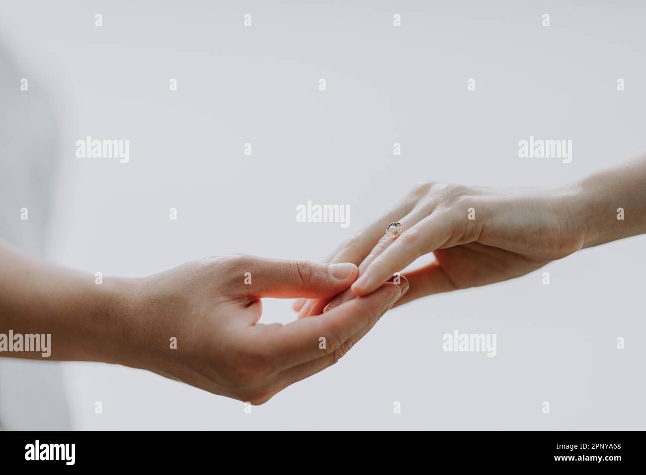 Una coppia che tiene le mani con un tocco leggero contro lo sfondo chiaro Foto Stock